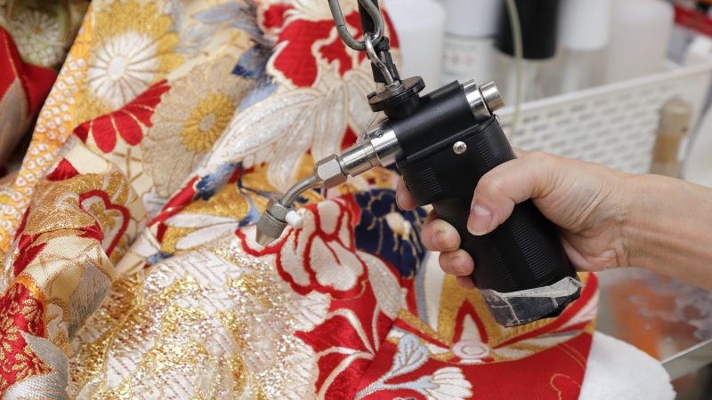 専用の機械を使用して袴の染み抜きを行うディアハートスタッフの手元
